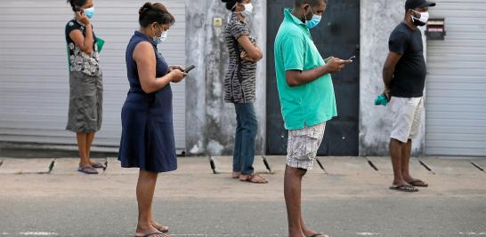 Las personas mantienen la distancia de un metro mientras hacen fila para comprar alimentos en un supermercado en Colombo, Sri Lanka.