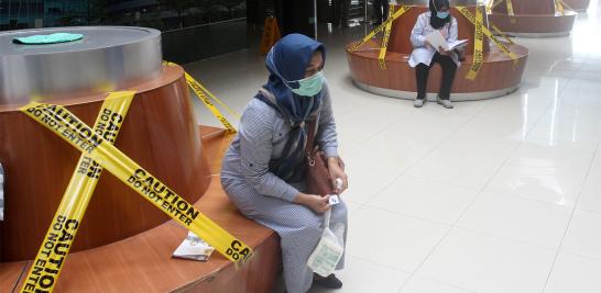 Los visitantes se sientan en bancos de distancia social en un hospital en Padang, provincia de Sumatera Occidental, Indonesia.