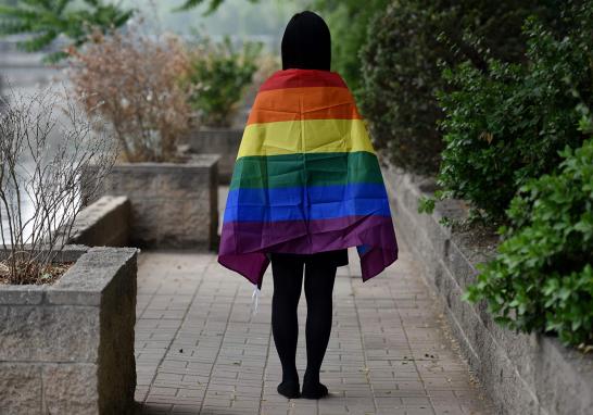 Un estudiante gay posa con una bandera del arcoíris en Beijing. La comunidad LGBT de China ha tenido un año difícil: los medios de noticias en línea han frenado la cobertura de los problemas de los dicha comunidad y las tiendas en línea han eliminado las ventas de productos con el tema del arcoíris.