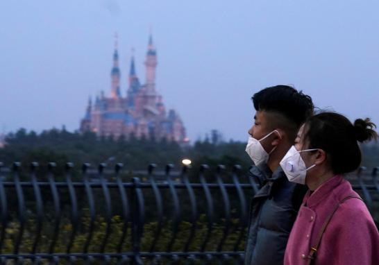 Visitors wearing masks walk past Shanghai Disney Resort, that will be closed during the Chinese Lunar New Year holiday following the outbreak of a new coronavirus, in Shanghai