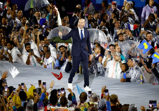 El exfutbolista y entrenador Zinedine Zidane fue el primero en realizar el recorrido de la llama olímpica desde el escenario donde se proclamó el inicio de los Juegos. Foto: Reuters