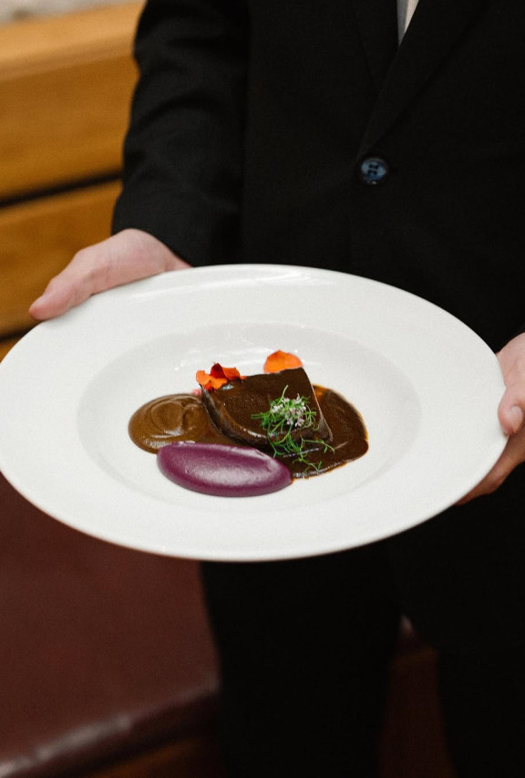 Lengua de res Wagyu cross braseada en cerveza, mole hecho en casa, puré de camote morado, frijoles orgánicos de Maximo Bistrot.