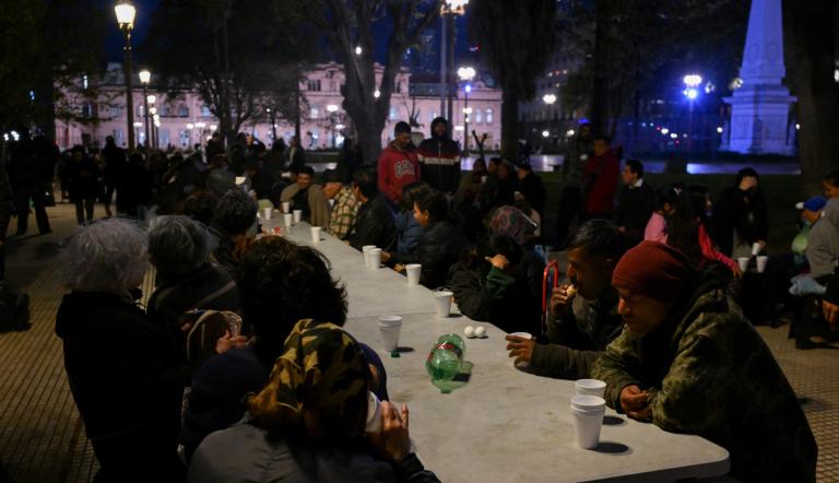 Personas comen alimentos proporcionados por la organización Red Solidaria en la Plaza de Mayo, frente al palacio presidencial de Casa Rosada en Buenos Aires, capital argentina.