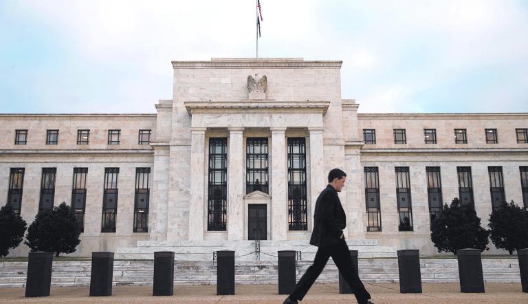 FILE PHOTO: A man walks past the Federal Reserve in Washington, December 16, 2015. The U.S. central bank is widely expected on Wednesday to hike its key federal funds rate by a modest 0.25 percent. It would be the first tightening in more than nine years and a big step on the tricky path of returning monetary policy to a more normal footing after aggressive bond-buying and near-zero borrowing costs. REUTERS/Kevin Lamarque/File Photo