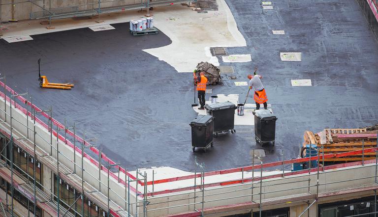 Roofer painting flat roof of a commercial building.