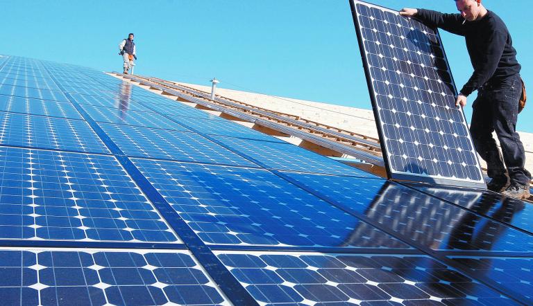 FILE PHOTO: Workers install solar panels on what will be the world's biggest integrated solar panel roof, 36,000 square metres spread over five hangars, at a farm in Weinbourg, Eastern France February 12, 2009. REUTERS/Vincent Kessler/File Photo