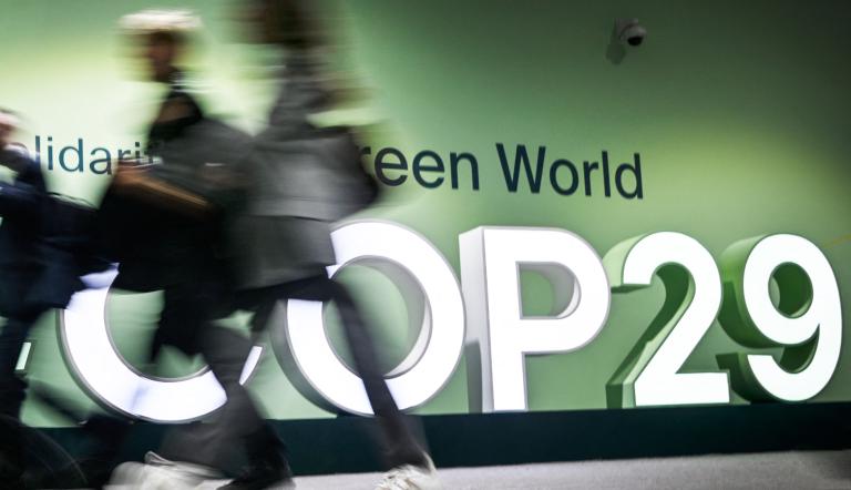 La gente pasa junto al logotipo de la Conferencia de las Naciones Unidas sobre el Cambio Climático de 2024 (COP29) en Bakú.