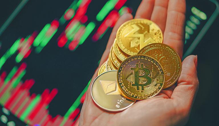 Hand holding various gold cryptocurrency coins with candle stick graph chart and digital background. Bitcoin, Ethereum, Litecoin, dogecoin.