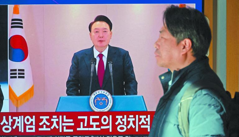 A person stands by a TV screen broadcasting South Korean President Yoon Suk Yeol delivering an address to the nation, at a railway station in Seoul, South Korea, December 12, 2024. REUTERS/Kim Hong-Ji