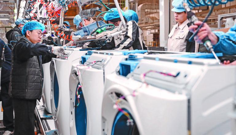 Employees work on a washing machine production line at a factory for Chinese home appliances and consumer electronics company Haier in Qingdao, in eastern China's Shandong province on February 18, 2024. (Photo by AFP) / CHINA OUT - China Out
