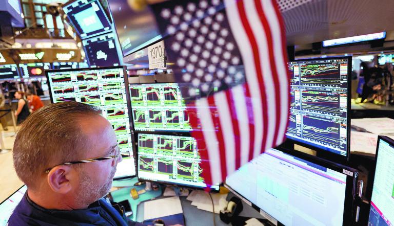 FILE PHOTO: A trader works at the New York Stock Exchange (NYSE) next to a U.S. flag, after Republican Donald Trump won the U.S. presidential election, in New York City, U.S., November 6, 2024. REUTERS/Andrew Kelly/File Photo
