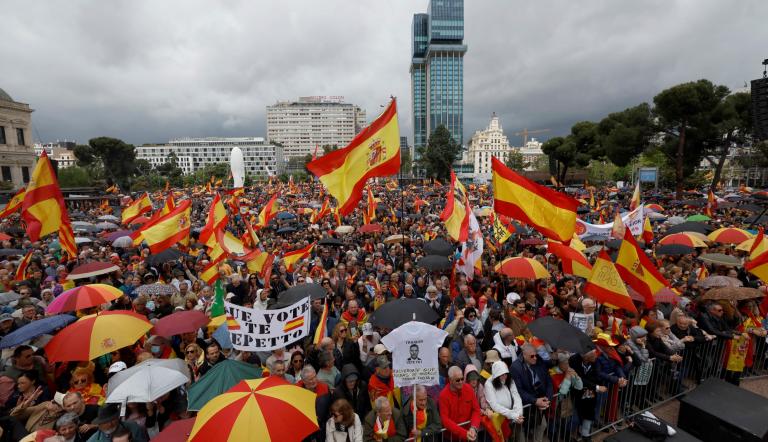 Manifestantes sostienen banderas de España durante una protesta antigubernamental convocada por simpatizantes de extrema derecha en Madrid.