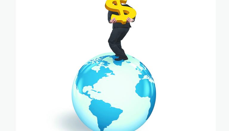Man carrying gold dollar sign standing on globe with world map, isolated on white background.