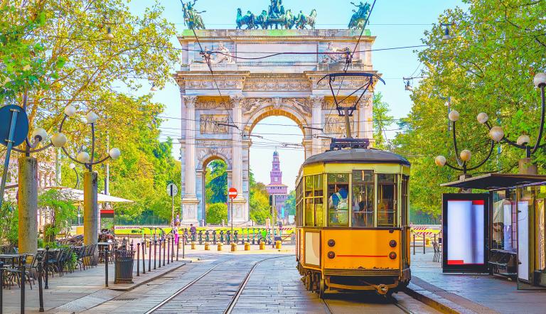 Vista del Arco de la Paz con tranvía amarillo en Milán, Italia. La ciudad con el mayor número de alojamientos certificados con el sello Travel Proud.