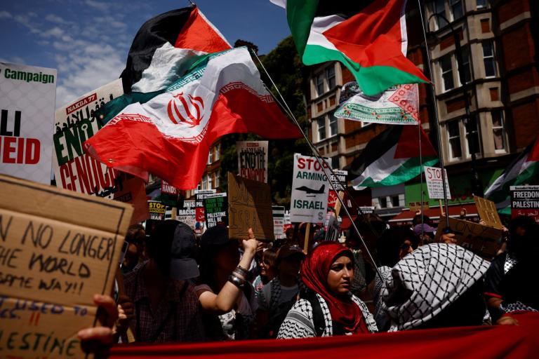 Manifestantes ondean banderas palestinas e iraníes y sostienen pancartas con la leyenda "Dejen de armar a Israel".