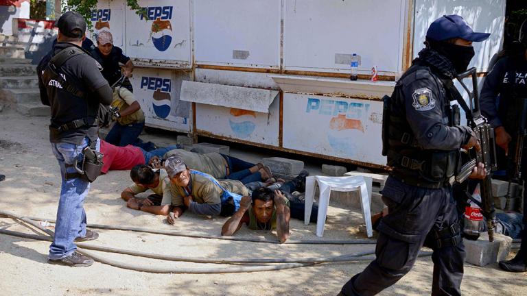 Guerrero policemen are seen during the arrest of a member of the Regional Coordinator of Community Authorities (CRAC) after a series of clashes that left at least 11 people dead at La Concepcion village, Acapulco municipality, in Guerrero state, Mexico, on January 7, 2018.At least 11 people were killed and 30 arrested during armed clashes among civilians, community guards and police in a rural area of Acapulco, in southern Mexico, the Guerrero government confirmed. / AFP PHOTO / FRANCISCO ROBLES