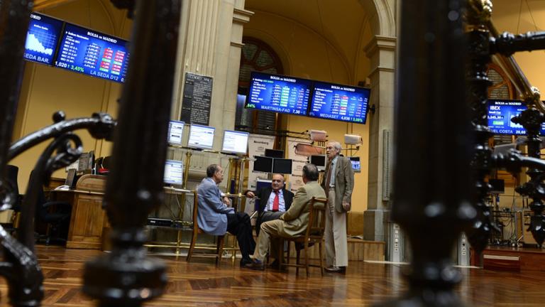 Traders sit next to the IBEX-35 index billboard on June 18, 2012 at Madrid