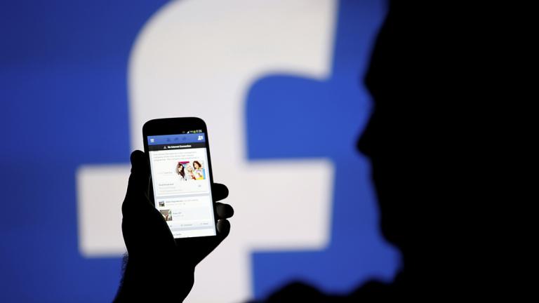 FILE PHOTO: A man is silhouetted against a video screen with an Facebook logo as he poses with an Samsung S4 smartphone in this photo illustration taken in the central Bosnian town of Zenica - FILE PHOTO: A man is silhouetted against a video screen with an Facebook logo as he poses with an Samsung S4 smartphone in this photo illustration August 14, 2013. REUTERS/Dado Ruvic/File Photo - NARCH/NARCH30