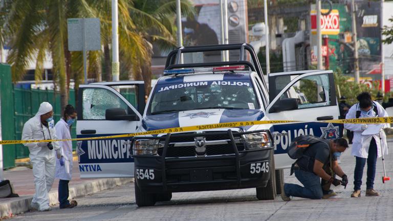 Forensic personnel and investigators collect evidence of an attack against a municipal police patrol car in Cancun, Quintana Roo state, Mexico on March 14, 2017. According to preliminary reports an indeterminate number of policemen were wounded in the attack carried out by gunmen on a motorcycle.  / AFP PHOTO / STR