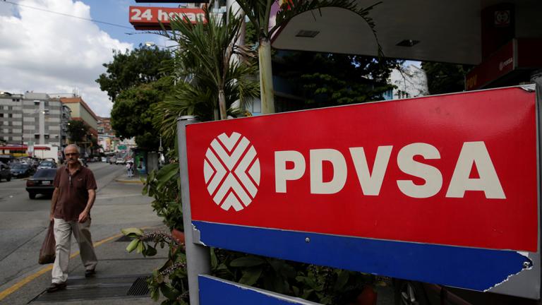 Man walks past PDVSA corporate logo at gas station in Caracas - A man walks past the corporate logo of the state oil company PDVSA at a gas station in Caracas, Venezuela December 1, 2017. REUTERS/Marco Bello