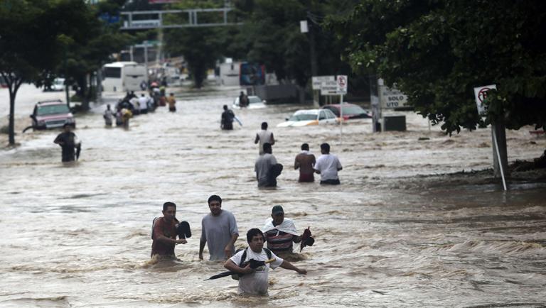 Residents attempt to flee from the flooded area in Acapulco, Guerrero state, Mexico, after heavy rains hit the area on September 16, 2013. Hurricane Ingrid weakened to tropical storm strength as it made landfall on the northeastern coast in the morning while the Pacific coast was reeling from the remnants of Tropical Storm Manuel, which dissipated after striking on the eve. Thousands of people were evacuated on both sides of the country as the two storms set off landslides and floods that damaged bridges, roads and homes.   AFP PHOTO AFP PHOTO / Pedro Pardo