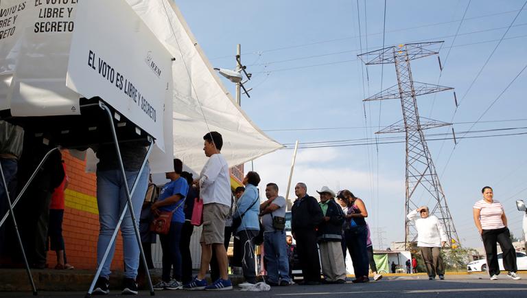 Woman prepares her ballot as other people wait in line to cast their votes at a polling station in Chimalhuacan