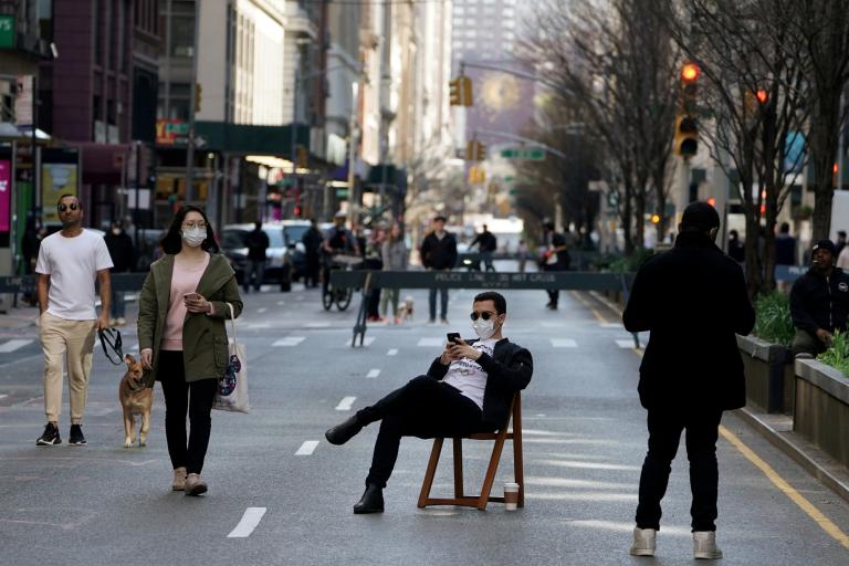 A man sits on a chair as people walk on Park Avenue that was closed to vehicular traffic during the outbreak of coronavirus disease (COVID-19), in the Manhattan borough of New York City