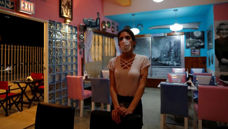 A waitress watches the TV as she waits for costumers in a restaurant, following the outbreake of the coronavirus disease (COVID-19), in Buenos Aires