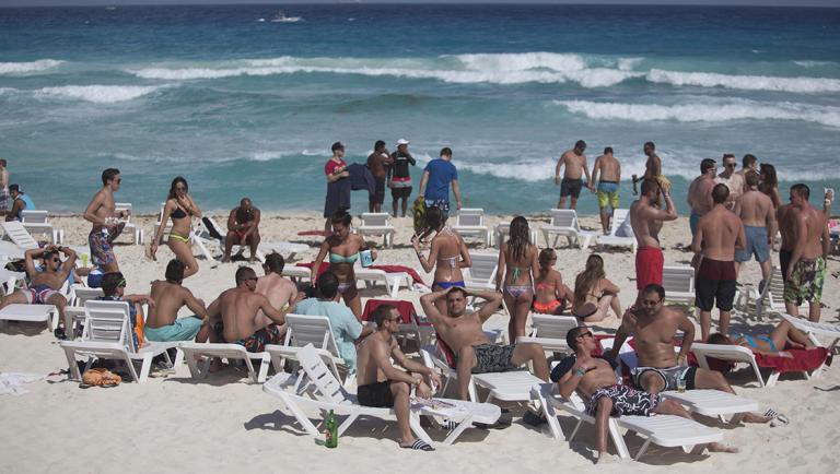 Spring breakers lay on the beach in Cancun