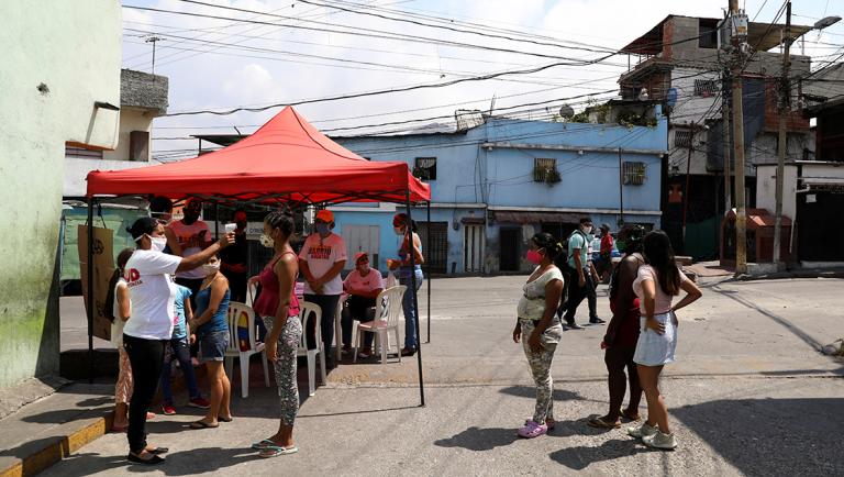 The temperature of a woman is tested by members of the Socialist party council at a checkpoint in the slum of Catia during a nationwide quarantine due to coronavirus disease (COVID-19) outbreak in Caracas