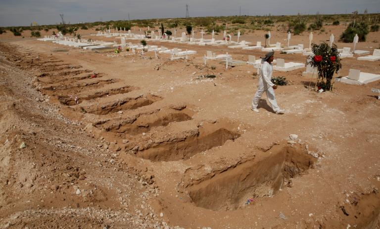 A grave digger walks by open graves for people who have died from the coronavirus disease (COVID-19) at a cemetery, in Ciudad Juarez, Mexico May 14, 2020. REUTERS/Jose Luis Gonzalez