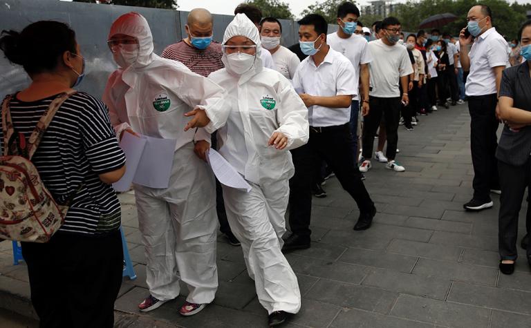 Medical workers attend to people lining up outside a site for nucleic acid tests in Beijing