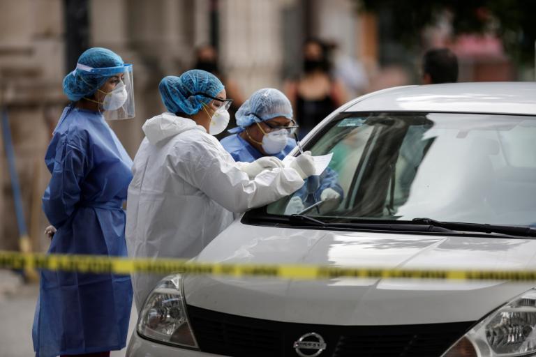 Healthcare workers talk to people before collecting swab samples to be tested for the coronavirus disease (COVID-19) at a drive-thru testing site in Monterrey