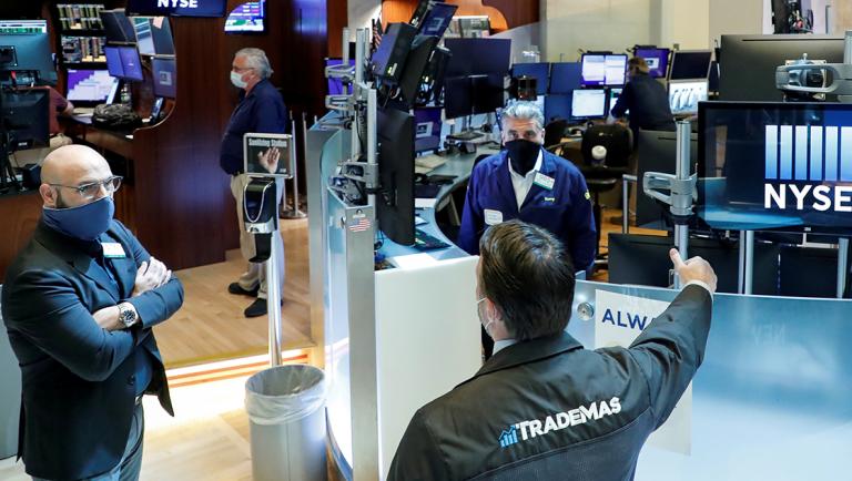 FILE PHOTO: Traders wearing masks work, on the first day of in person trading since the closure during the outbreak of the coronavirus disease (COVID-19) on the floor at the NYSE in New York