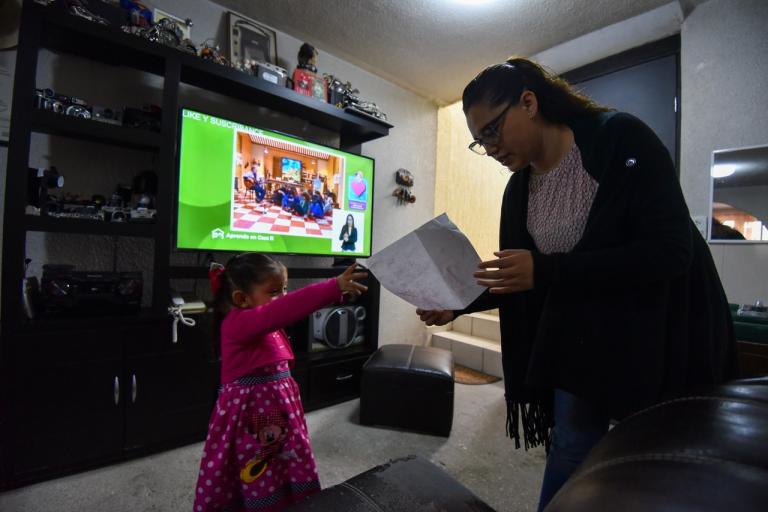 El inicio del ciclo escolar 2020-2021 es diferente por la pandemia de COVID-19, desde muy temprana hora comenzaron las clases de ma era virtual, los estudiantes se sentaron frente a la televisión para poder iniciar sus actividades, teniendo al lado todos sus materiales como libretas, lápices, libros, celular y control remoto; su mamá revisa el trabajo de sus dos hijos para poder mandar las evidencias a sus profesoras, y más tarde se tendrá sesión por internet para aclarar dudas. FOTO: CRISANTA ESPINOSA AGUILAR /CUARTOSCURO.COM