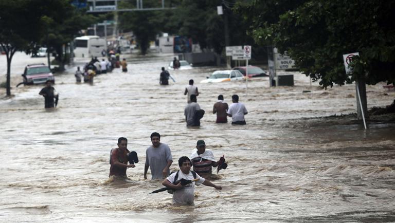 Residents attempt to flee from the flooded area in Acapulco, Guerrero state, Mexico, after heavy rains hit the area on September 16, 2013. Hurricane Ingrid weakened to tropical storm strength as it made landfall on the northeastern coast in the morning while the Pacific coast was reeling from the remnants of Tropical Storm Manuel, which dissipated after striking on the eve. Thousands of people were evacuated on both sides of the country as the two storms set off landslides and floods that damaged bridges, roads and homes.   AFP PHOTO AFP PHOTO / Pedro Pardo