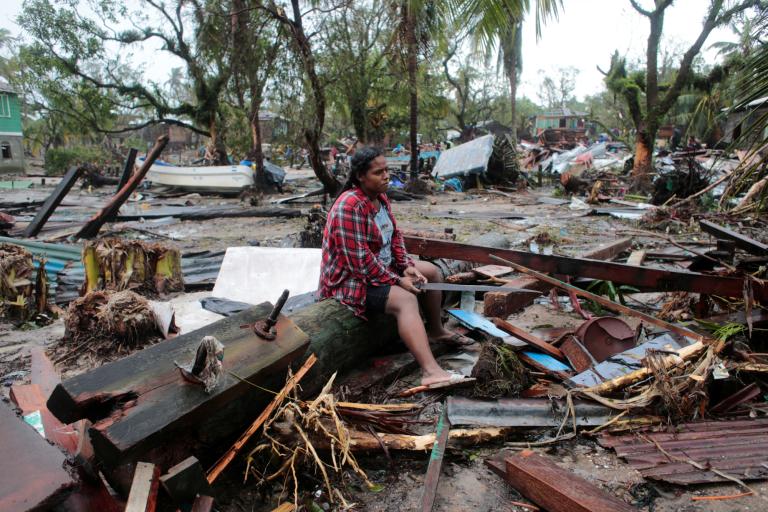 Una mujer sentada sobre un poste de energía derribado mientras contempla su casa destruida tras el paso del huracán Iota, en Puerto Cabezas, Nicaragua. Foto: Reuters