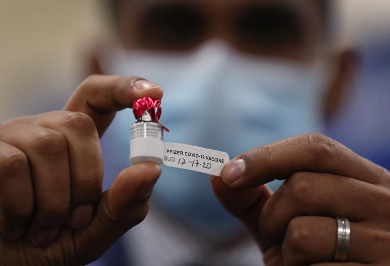 Un empleado del Broward Health Medical Center en Florida manipula un frasco con la vacuna contra el Covid-19 de Pfizer-BioNTech, el 17 de diciembre. Foto: AFP