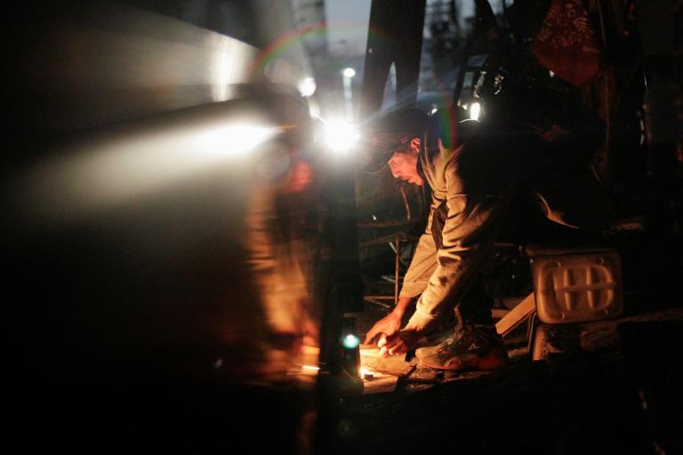 A man places firewood on a bonfire to heat tortillas outside their home during an electrical outage in Monterrey