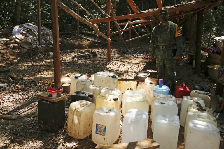 A soldier stands next to plastic containers at an area where military authorities eradicated a coca leaf plantation and dismantled a lab to process the drug, in El Porvenir