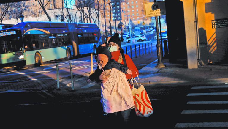 A woman wearing a protective carries a baby amid the spread of the coronavirus disease (COVID-19) near Yankee Stadium in the Bronx borough of New York