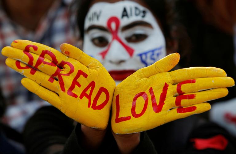 A student poses as she displays her face and hands painted with messages during an HIV/AIDS awareness campaign on the eve of World AIDS Day in Chandigarh