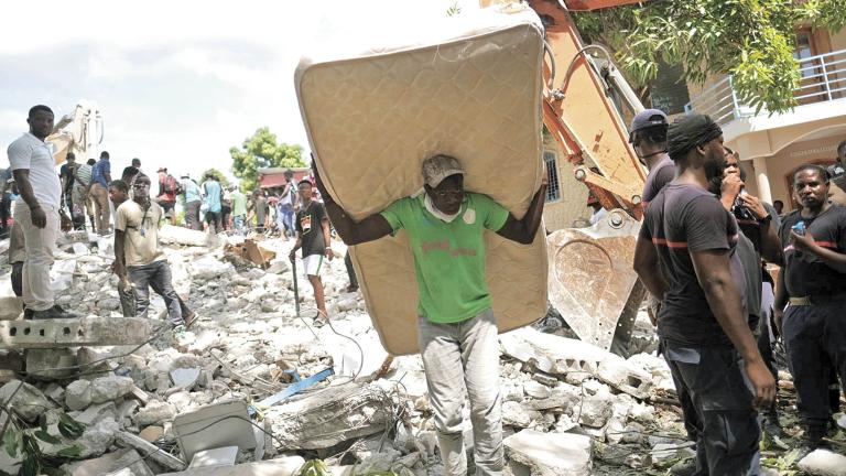 A man carries a mattress from the site of a collapsed hotel after Saturday's 7.2 magnitude quake, in Les Cayes, Haiti August 16, 2021. REUTERS/Ricardo Arduengo