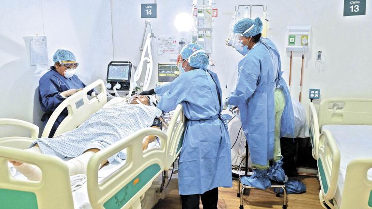 A group of doctors treats a Covid-19 patient at the hospital of the Mexican Institute of Social Security (IMSS) in Mexico City on June 2, 2021. - 7,000 people suffering from COVID-19 have been treated at the field hospital at the Hermanos Rodriguez racetrack since it was set up a year ago. The hospital will be dismantled to host the 2021 Mexico F1 GP in October. (Photo by ALFREDO ESTRELLA / AE / AFP)