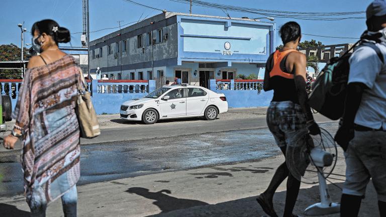 People walk near El Capri Police Station in Arroyo Naranjo Municipality in Havana, on July 13,  2021. - Cuban authorities have cut access to major social media platforms in an effort to stem the flow of information in the face of anti-government protesters, a web monitoring organization said. (Photo by YAMIL LAGE / AFP)