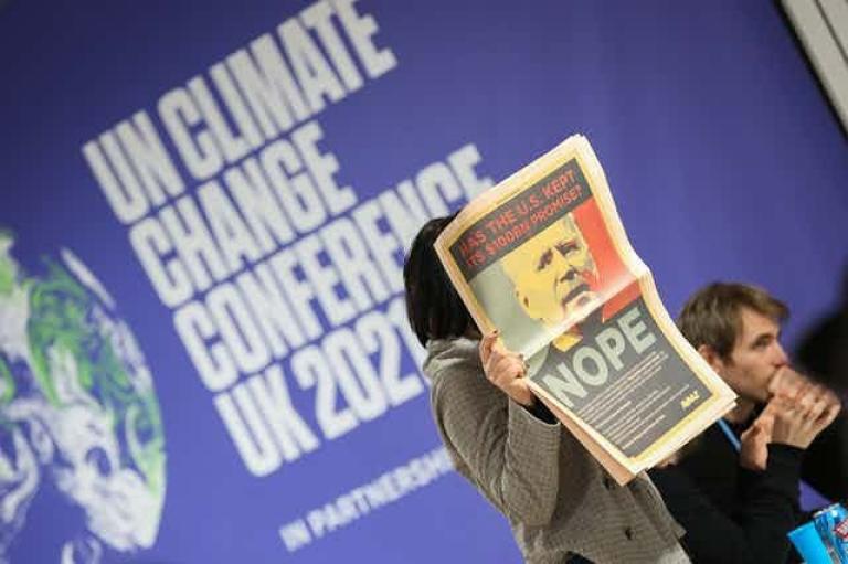 Una delegada en la COP26 muestra la página de un periódico en la que se critica a Joe Biden durante la sesión de clausura de la conferencia climática. Flikr / UNclimatechange / KiaraWorth, CC BY-NC-SA