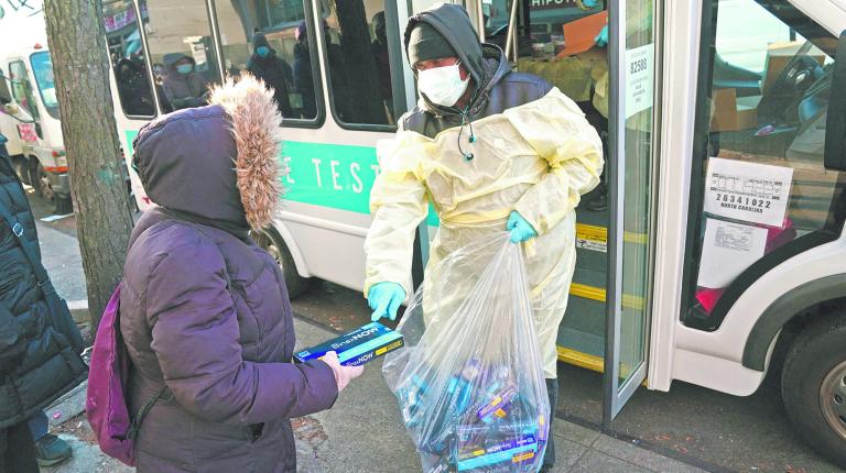 TOPSHOT - Binax Covid-19 testing kits are handed out in the Bensonhurst section of the Brooklyn borough of New York City on December 23, 2021. - The resumption of holiday travel coupled with the rapidly spreading Omicron variant left Americans scrambling  to find at-home Covid tests, leading multiple major distributors to limit the number of kits per customer. Amazon, as well as vendors on its platform, began limiting the number of tests per person on December 22. National pharmaceutical chains CVS and Walgreens announced a maximum limit of six and four kits, respectively, per customer. (Photo by Bryan R. Smith / AFP)