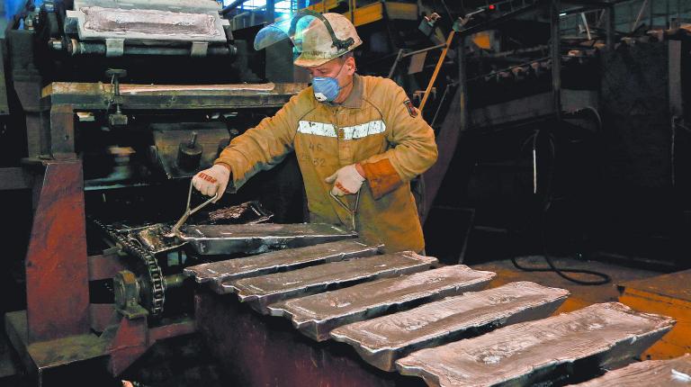 FILE PHOTO: A worker controls forming of aluminium ingots on a conveyor belt at the foundry shop of the Rusal Krasnoyarsk aluminium smelter in Krasnoyarsk