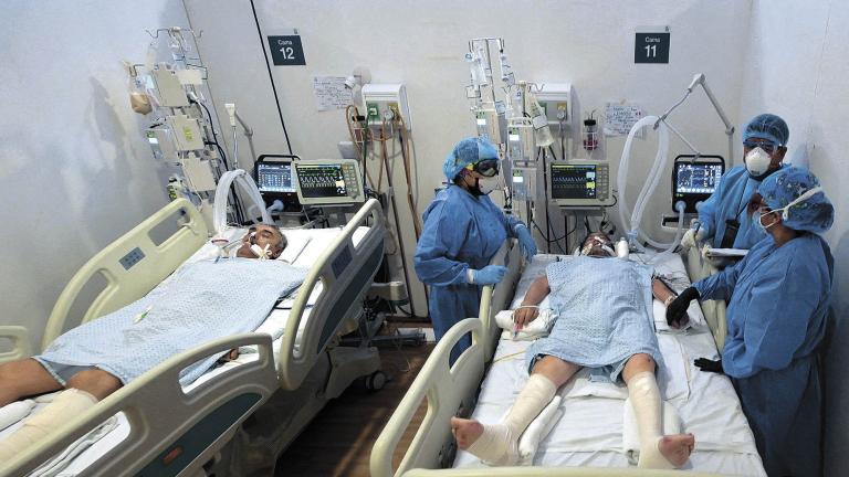 A group of doctors treats a Covid-19 patient at the hospital of the Mexican Institute of Social Security (IMSS) in Mexico City on June 2, 2021. - 7,000 people suffering from COVID-19 have been treated at the field hospital at the Hermanos Rodriguez racetrack since it was set up a year ago. The hospital will be dismantled to host the 2021 Mexico F1 GP in October. (Photo by ALFREDO ESTRELLA / AE / AFP)