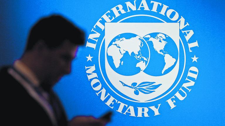 FILE PHOTO: A participant stands near a logo of IMF at the International Monetary Fund - World Bank Annual Meeting 2018 in Nusa Dua